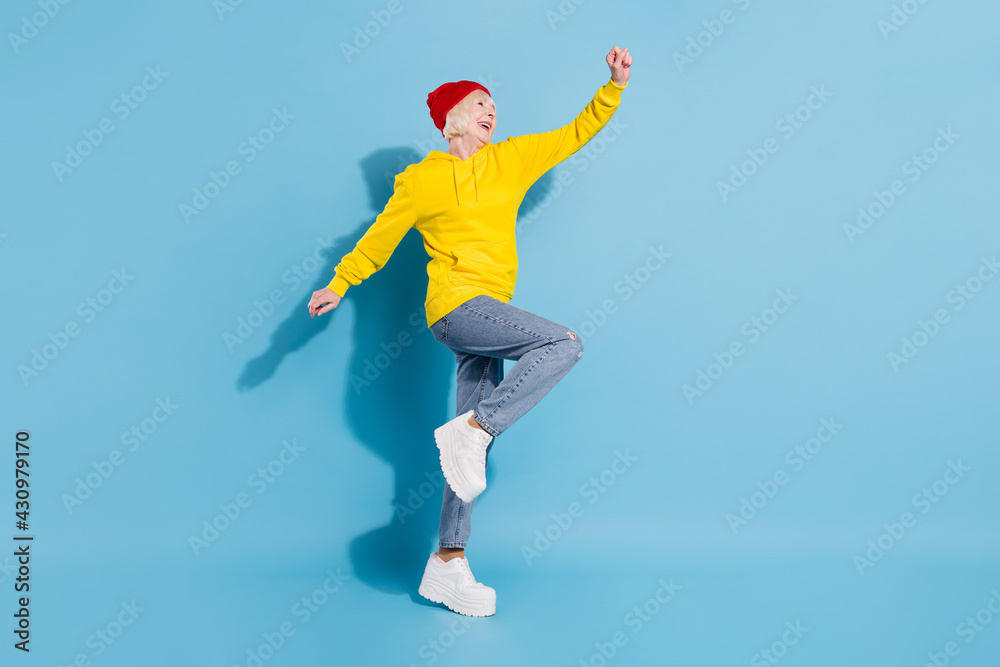 Full body profile side photo of dreamy happy old woman look empty space go isolated on blue color background Full body profile side photo of dreamy happy old woman look empty space go isolated on blue color background