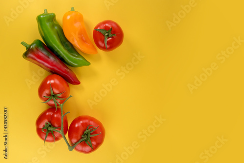 tomatoes and peppers arranged as frame on yellow background with copy space