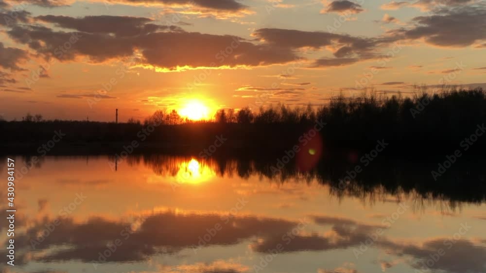 Orange sunset over the river with clouds in the sky reflecting at water surface. Orange sunset over the river with clouds in the sky reflecting at water surface.