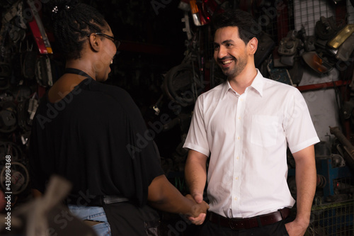 Man shakes hand with woman. Diversity of two people, caucasian business manager smile and shake hand with black African worker woman in factory-warehouse