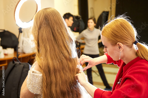 A costume designer or stylist helps a model prepare for a photo shoot in the studio photo