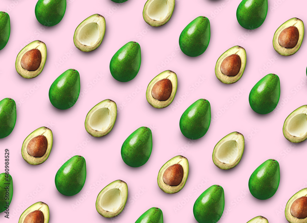 Avocado cut in half with bone isolated colored background. Avocado on a pink background Avocado cut in half with bone isolated colored background. Avocado on a pink background