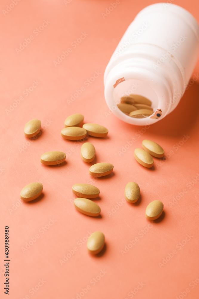 herbal medicine spilling from a container on orange background herbal medicine spilling from a container on orange background