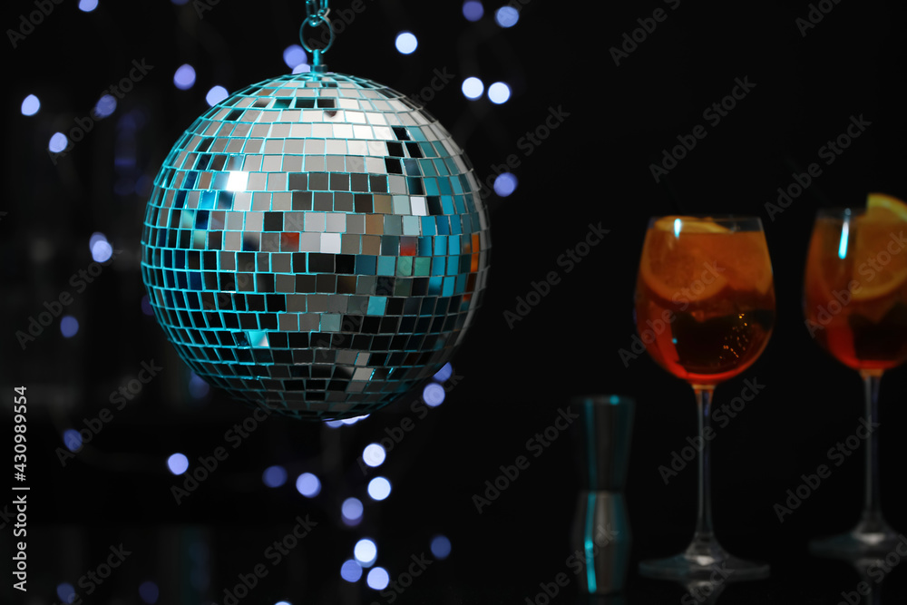 Obraz premium Shiny disco ball hanging over bar counter with cocktails in nightclub, space for text