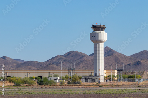 Air traffic control tower at a small airport against a blue sky with surrounding mountains