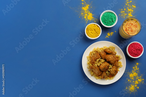 Traditional Indian food and color powders on blue background, flat lay with space for text. Holi festival celebration