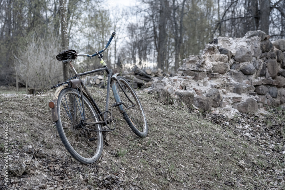 An old rusted bike is left by stone wall.