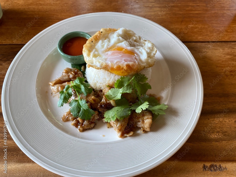Top view of fried pork and egg on rice served on white plate. Thai dish style, fast food. Top view of fried pork and egg on rice served on white plate. Thai dish style, fast food.