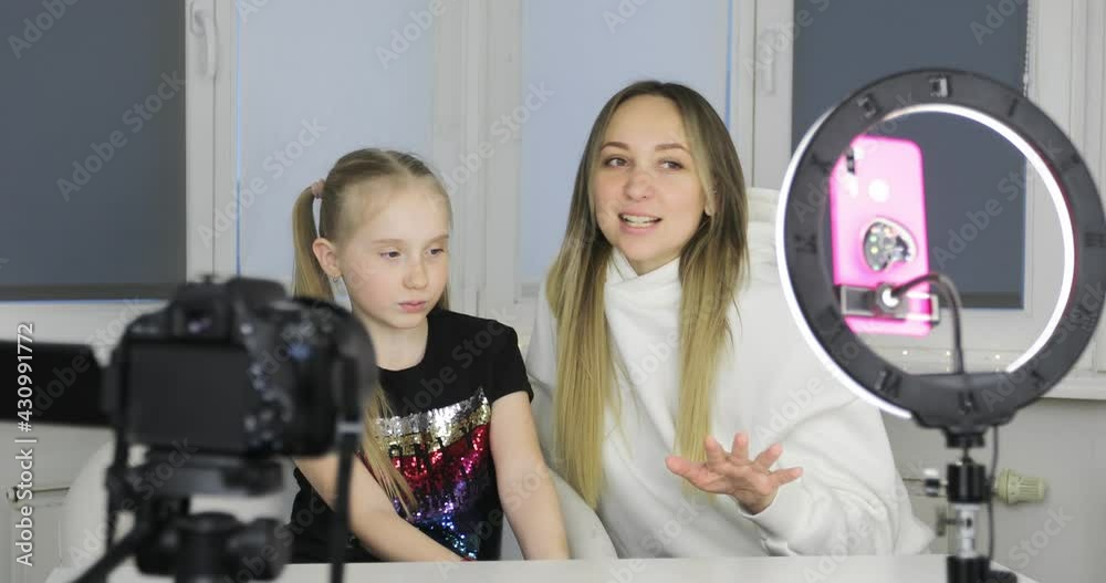 Mom and daughter are recording a video blog on a smartphone camera. A woman and a schoolgirl talk over video communication during quarantine. Mom and daughter are recording a video blog on a smartphone camera. A woman and a schoolgirl talk over video communication during quarantine.