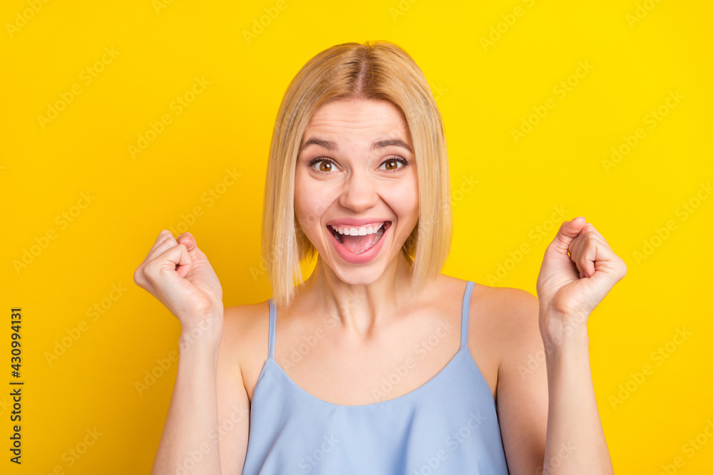 Photo of hooray cute blond short hair lady hands fists wear blue top isolated on vivid yellow color background Photo of hooray cute blond short hair lady hands fists wear blue top isolated on vivid yellow color background