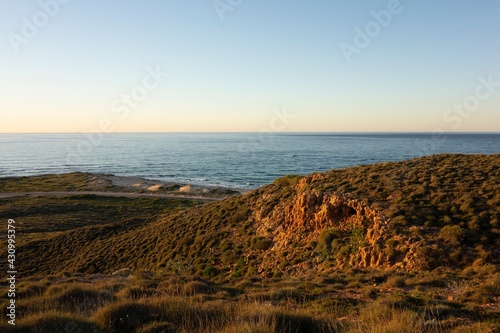 Landscape of coastline and rocks near Coastline and Vlamingh Head Precinct lighthouse at sunset
