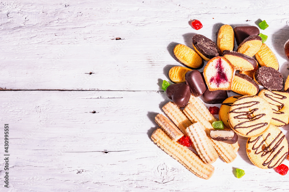 Assorted various cookies and cupcakes scattered on wooden boards background