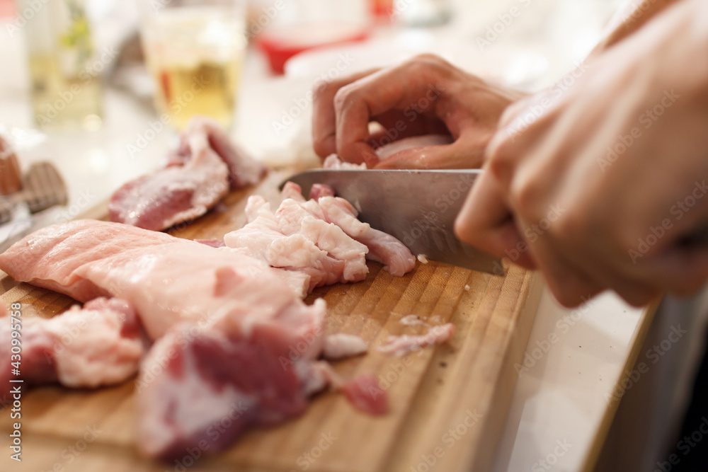 A man cook cuts pork meat with a knife. Cooking Concept