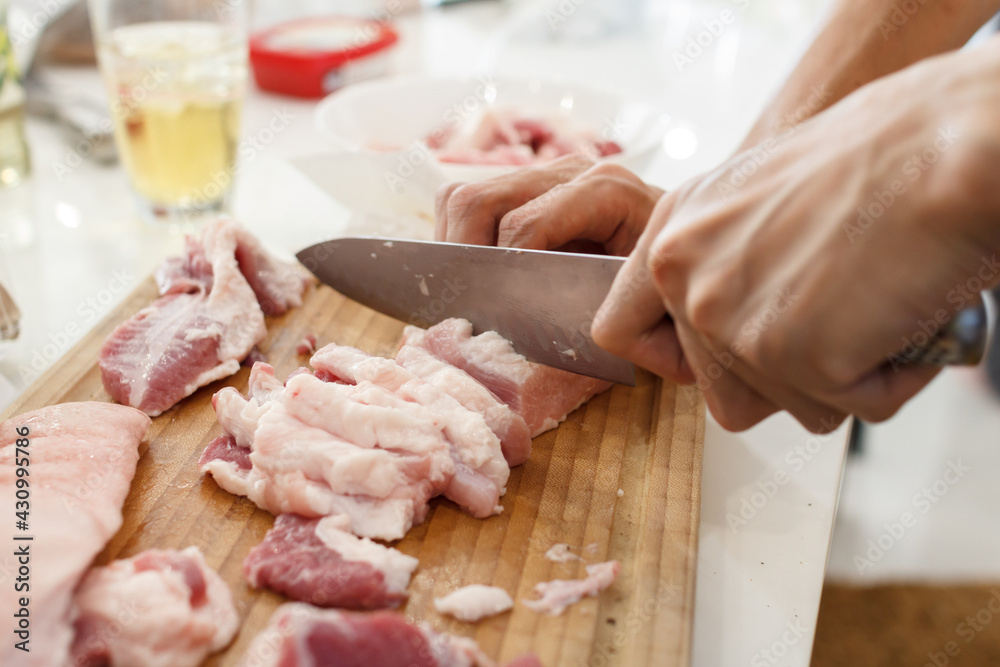 A man cook cuts pork meat with a knife. Cooking Concept