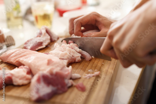 A man cook cuts pork meat with a knife. Cooking Concept