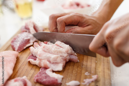 A man cook cuts pork meat with a knife. Cooking Concept
