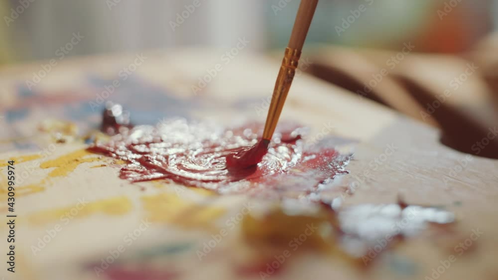 Close up selective focus shot of blending paint colors with brush on wooden palette Close up selective focus shot of blending paint colors with brush on wooden palette