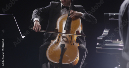 Young man playing double bass against black background