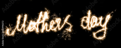 The inscription Mothers day on a black background with sparklers using a simulated long exposure.