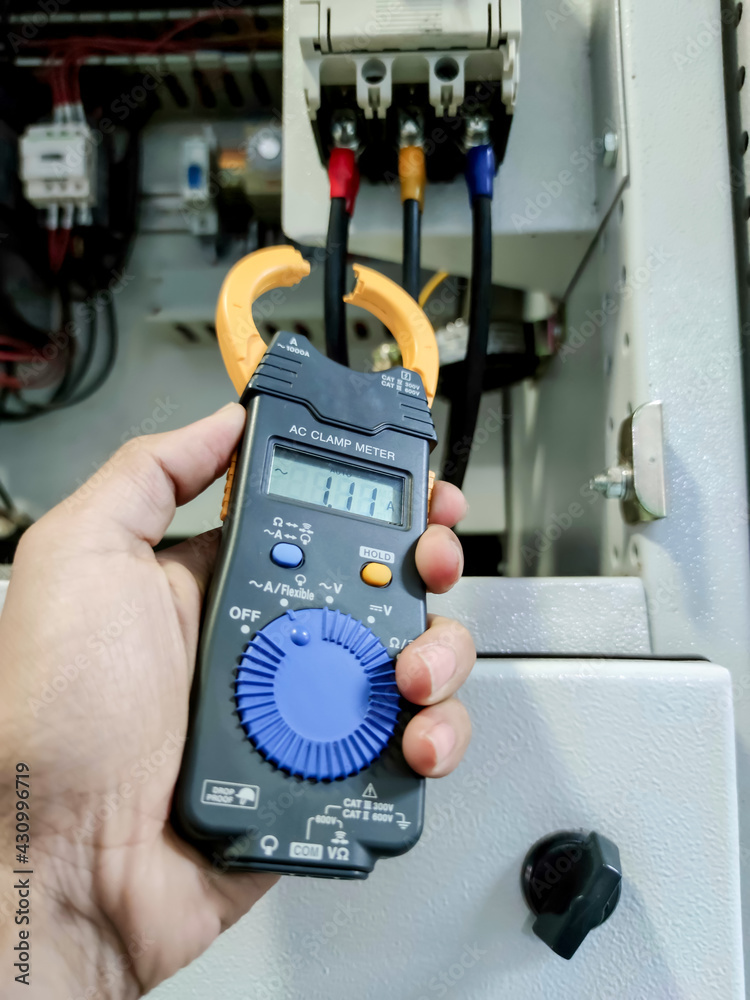 Inspection and measurement of electrical systems with meters in industrial plants.  Measuring the current from the circuit breaker with an electric meter.  Clamp meter