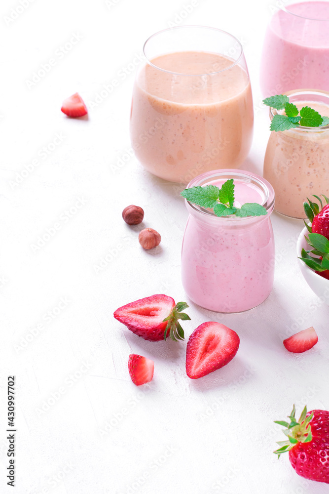 Pink and yellow smoothies topped with mint in glass jars on the white table. Healthy drink and kids food Pink and yellow smoothies topped with mint in glass jars on the white table. Healthy drink and kids food