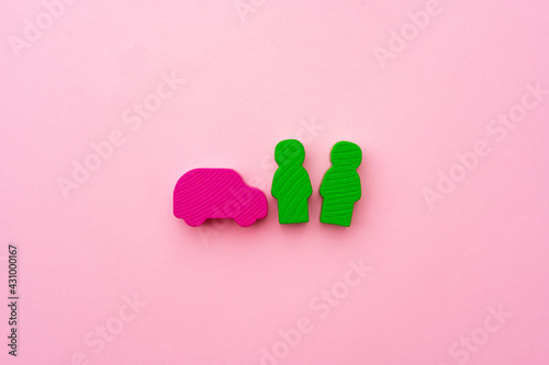 Wooden toys of people and car on pink background