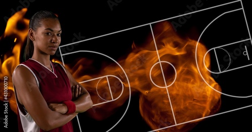 Composition of female basketball player over basketball court and flames