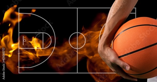 Composition of midsection of basketball player holding basketball over basketball court and flames