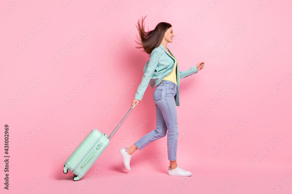 Full length profile side photo of charming pretty young lady walk empty space travel bag isolated on pink color background Full length profile side photo of charming pretty young lady walk empty space travel bag isolated on pink color background