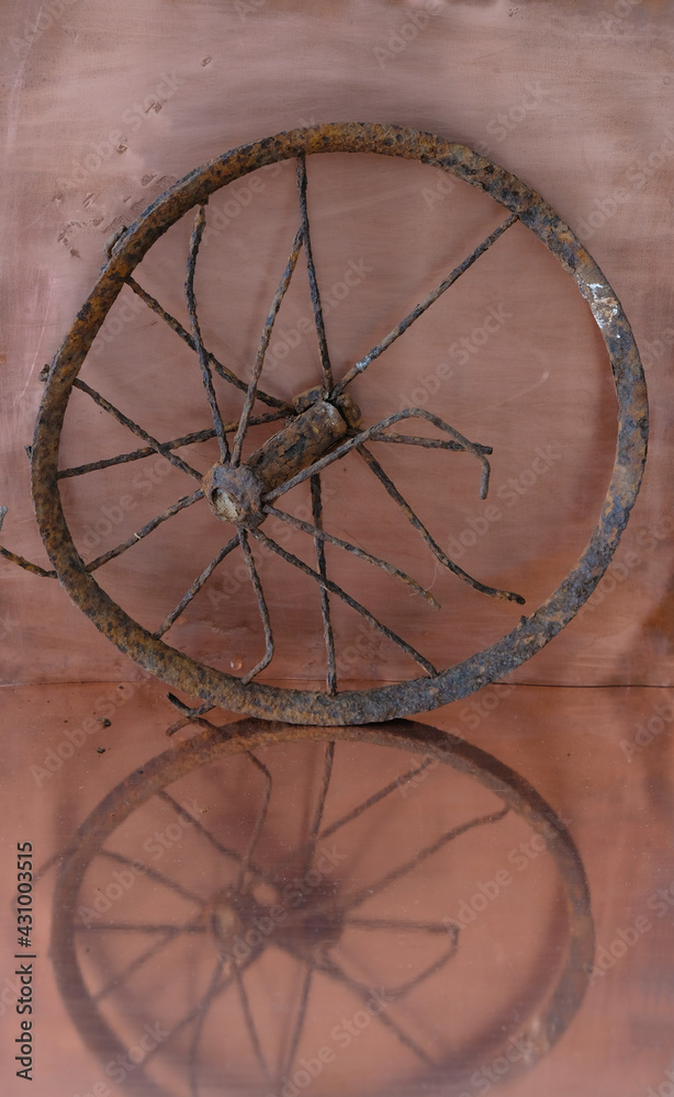 Vintage rusty wheel from a pram on a copper background. Reflection. Vertical image. Copy space. 