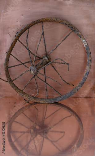 Vintage rusty wheel from a pram on a copper background. Reflection. Vertical image. Copy space. 