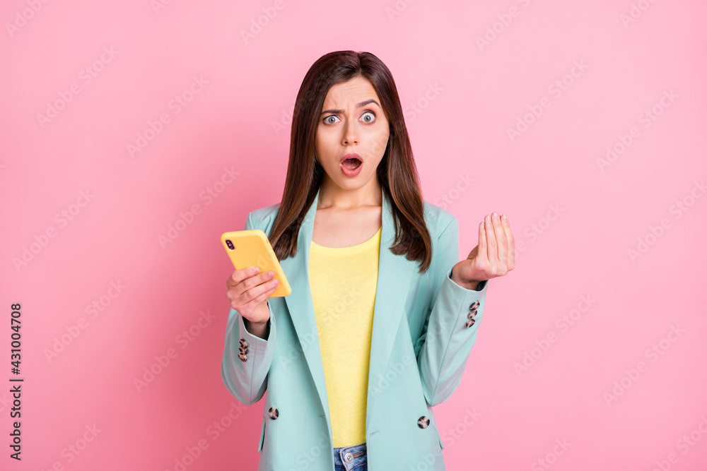 Photo portrait of confused woman showing italian hand sign holding phone in one hand isolated on pastel pink colored background Photo portrait of confused woman showing italian hand sign holding phone in one hand isolated on pastel pink colored background