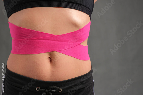 Kinesiology medical tapes on the belly of a young woman