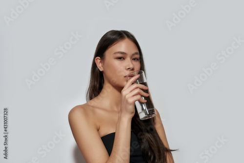 Young asian girl drinking water from glass