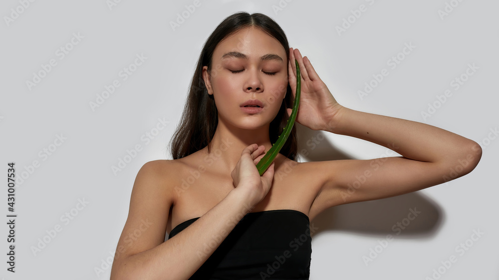 Fototapeta premium Young asian woman with closed eyes holding aloe leaf