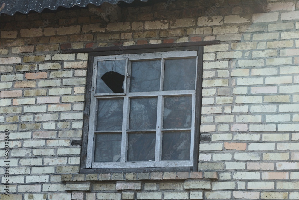 one old large square window with a broken window on a brown brick wall