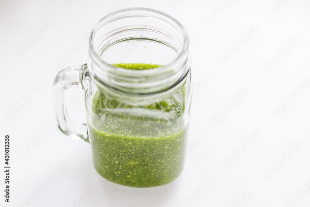 Green fresh smoothie from raw vegetables in glass jar on white background Green fresh smoothie from raw vegetables in glass jar on white background