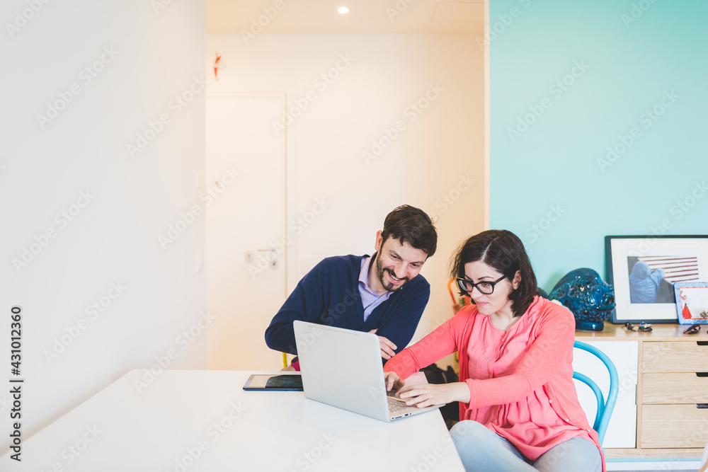 Adult couple sitting home remote working using computer Adult couple sitting home remote working using computer