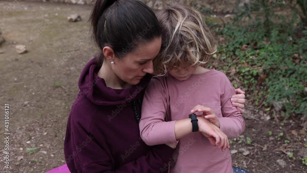 Mom explaining to son how to use wristwatch outdoors Mom explaining to son how to use wristwatch outdoors
