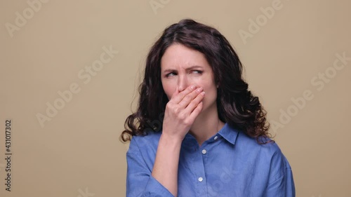 Bad smell reaction. Brunette woman grabbing nose with hands to avoid unpleasant odor. Female covering face from disgusting aroma, fart stench. Millennial girl react to stinky gas, studio shot portrait