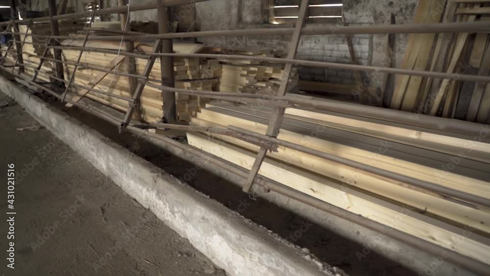 Wooden beams stored in shed seperated with iron fence Gimbal shot Wooden beams stored in shed seperated with iron fence Gimbal shot