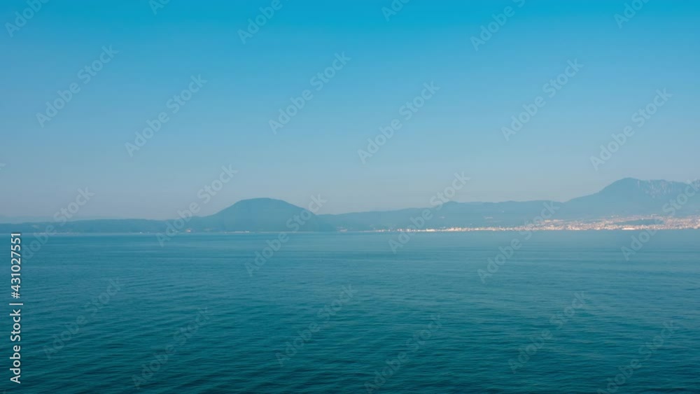 Beppu, Japan. Arriving to the Beppu, Japan port on a boat. Time-lapse of a boat riding through the sea with city and mountains at the background Beppu, Japan. Arriving to the Beppu, Japan port on a boat. Time-lapse of a boat riding through the sea with city and mountains at the background