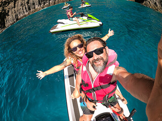 Happy adult couple have fun on jet sky activity escursion in summer holiday vacation at the sea - ocean active people take selfie picture and smile with happiness and freedom - cheerful lifestyle
