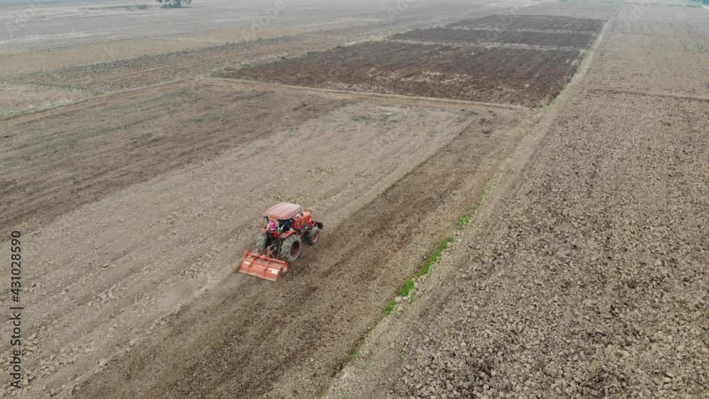 Tractor working on rice plantation for rice growth after harvest aerial view Tractor working on rice plantation for rice growth after harvest aerial view