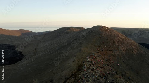 people sitting on a mountain watching a volcano photo