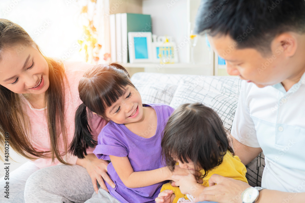 Happy Asian family playing together at sofa in home living room Happy Asian family playing together at sofa in home living room