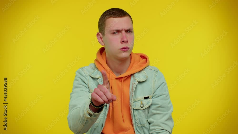 I am warning you. Student boy shakes finger and saying no, be careful, scolding and giving advice to avoid danger mistake, disapproval sign. Young man studio shot isolated on yellow wall background I am warning you. Student boy shakes finger and saying no, be careful, scolding and giving advice to avoid danger mistake, disapproval sign. Young man studio shot isolated on yellow wall background