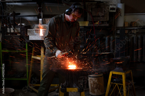 The blacksmith forges, sparks fly. Traditional metalworking process in a forge.
