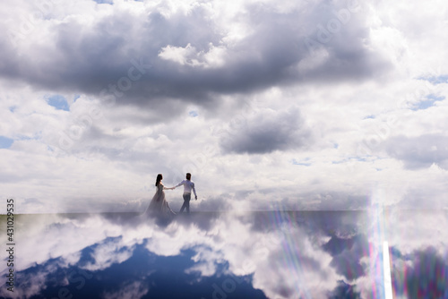 View from distance.newlyweds walk in the clouds. Fabulous honeymoon. Concept of honeymoon © IVASHstudio