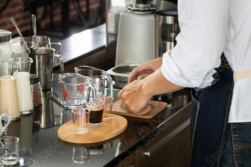 Young Barista preparing and making espresso with coffee machine. Barista making cappuccino in a coffee shop. Barista holding portafilter tamping and preparing cup of coffee.